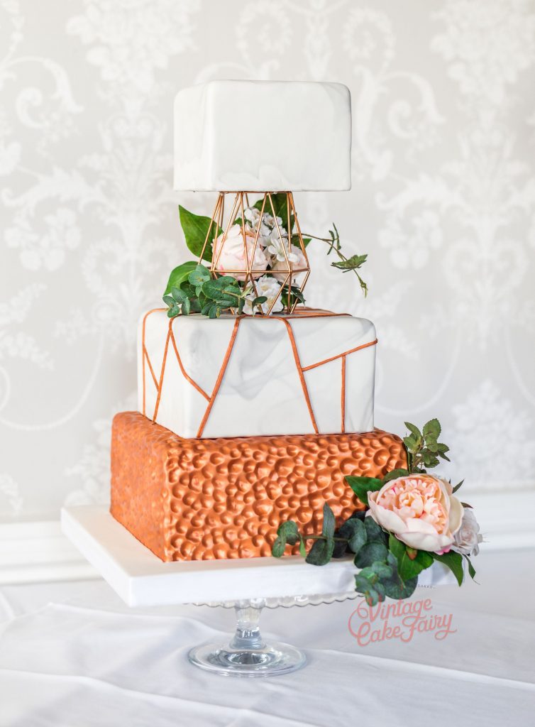 three tier wedding cake with copper effect bottom tier, geometric tier separator and fresh flowers
